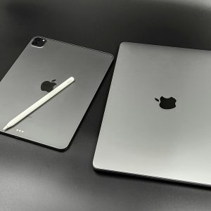 A stylish composition featuring a sleek Apple iPad and MacBook paired with an Apple Pencil on a modern black background.