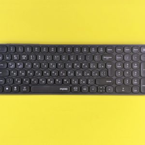 A sleek black wireless keyboard displayed against a vibrant yellow background, perfect for tech themes.