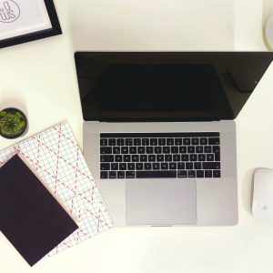 Minimalist workspace featuring a laptop, notepads, and a mouse in Budapest.